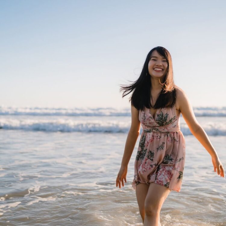  Young Asian woman walking on beach Image by tirachardz on Freepik